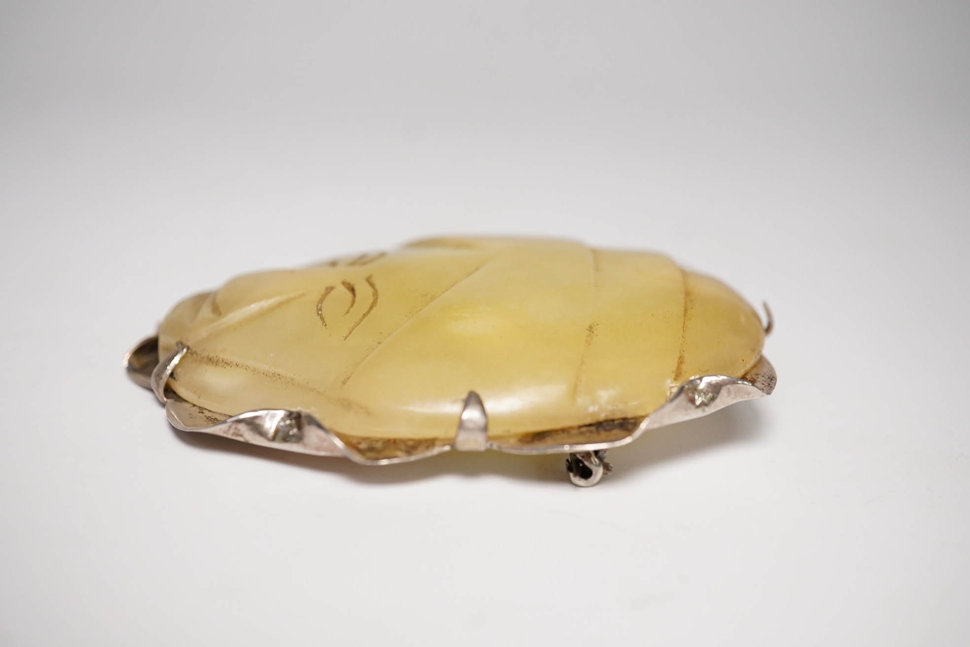 A Mexican silver mounted jadeite brooch, the jadeite face possibly pre-Columbian, 6cm high. Condition - fair, chip to top of brooch